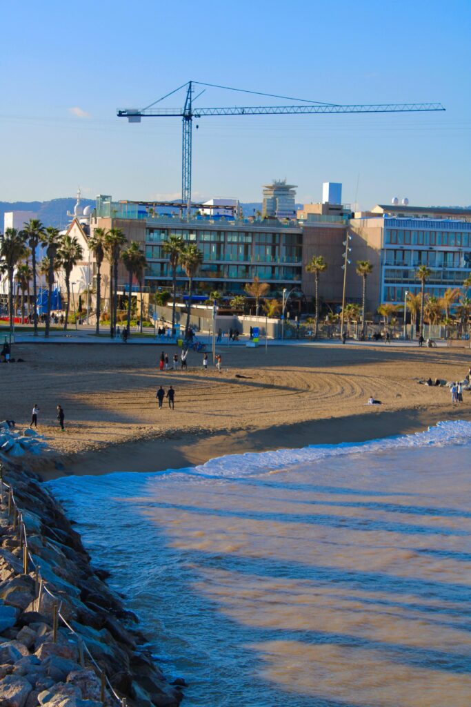Coastal cityscape featuring a beach and a construction crane.